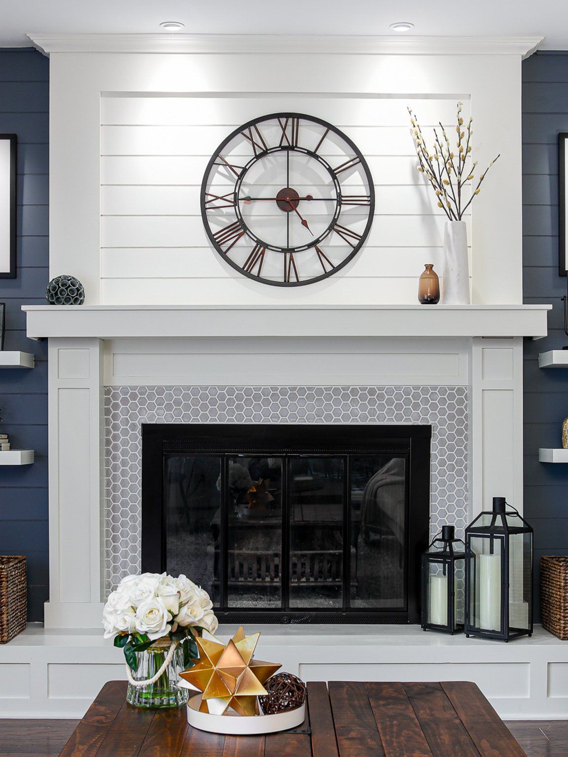 A living room with a fireplace and a clock on the wall above it.