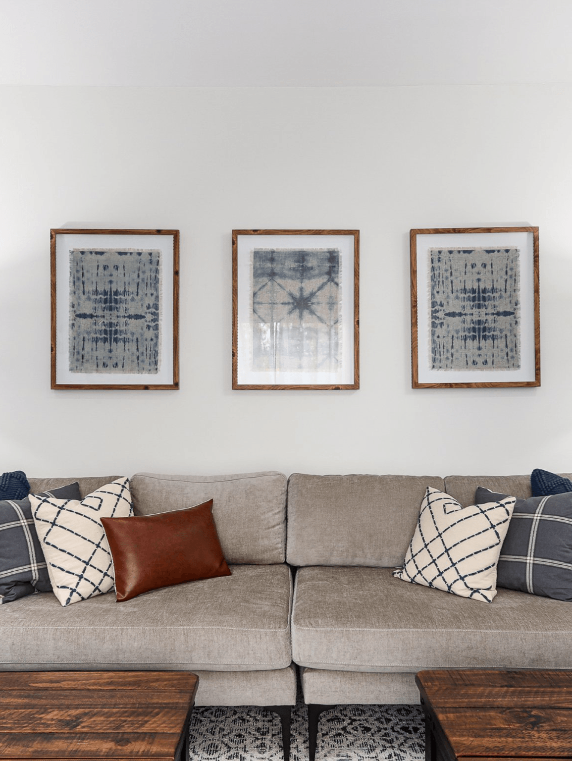 A living room with a couch and three paintings on the wall.