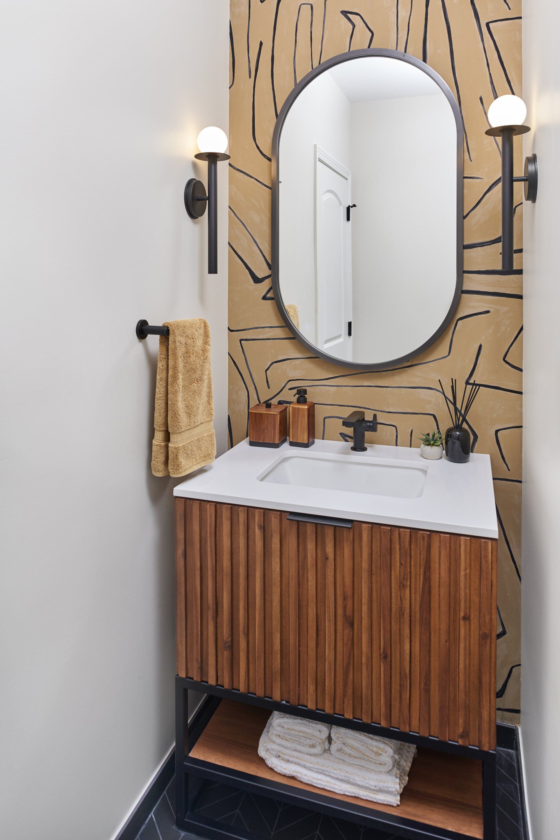 A bathroom with a sink , mirror and towels.