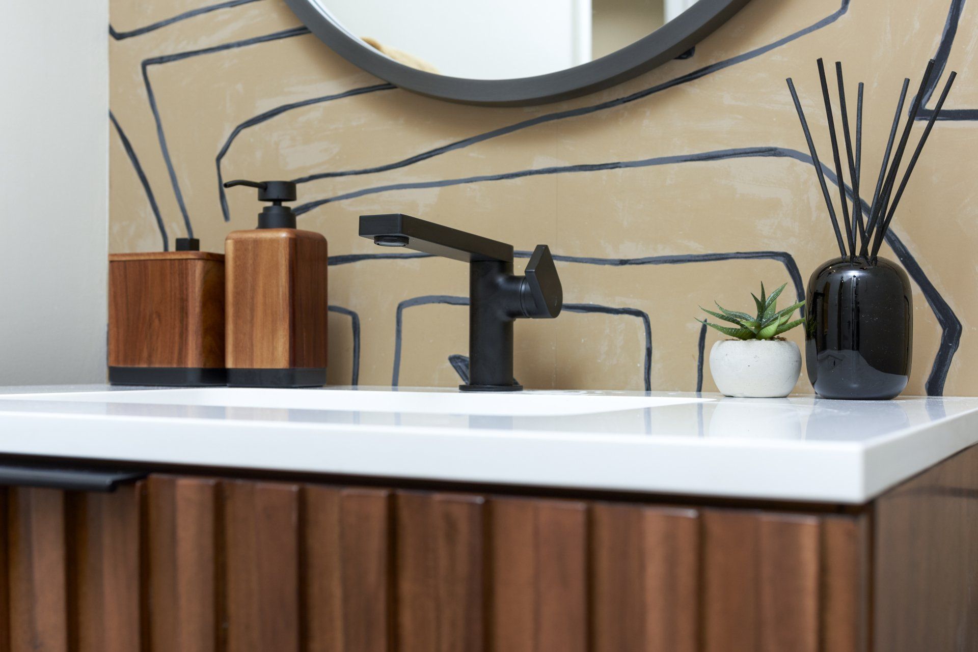 A bathroom with a sink , mirror and soap dispensers.