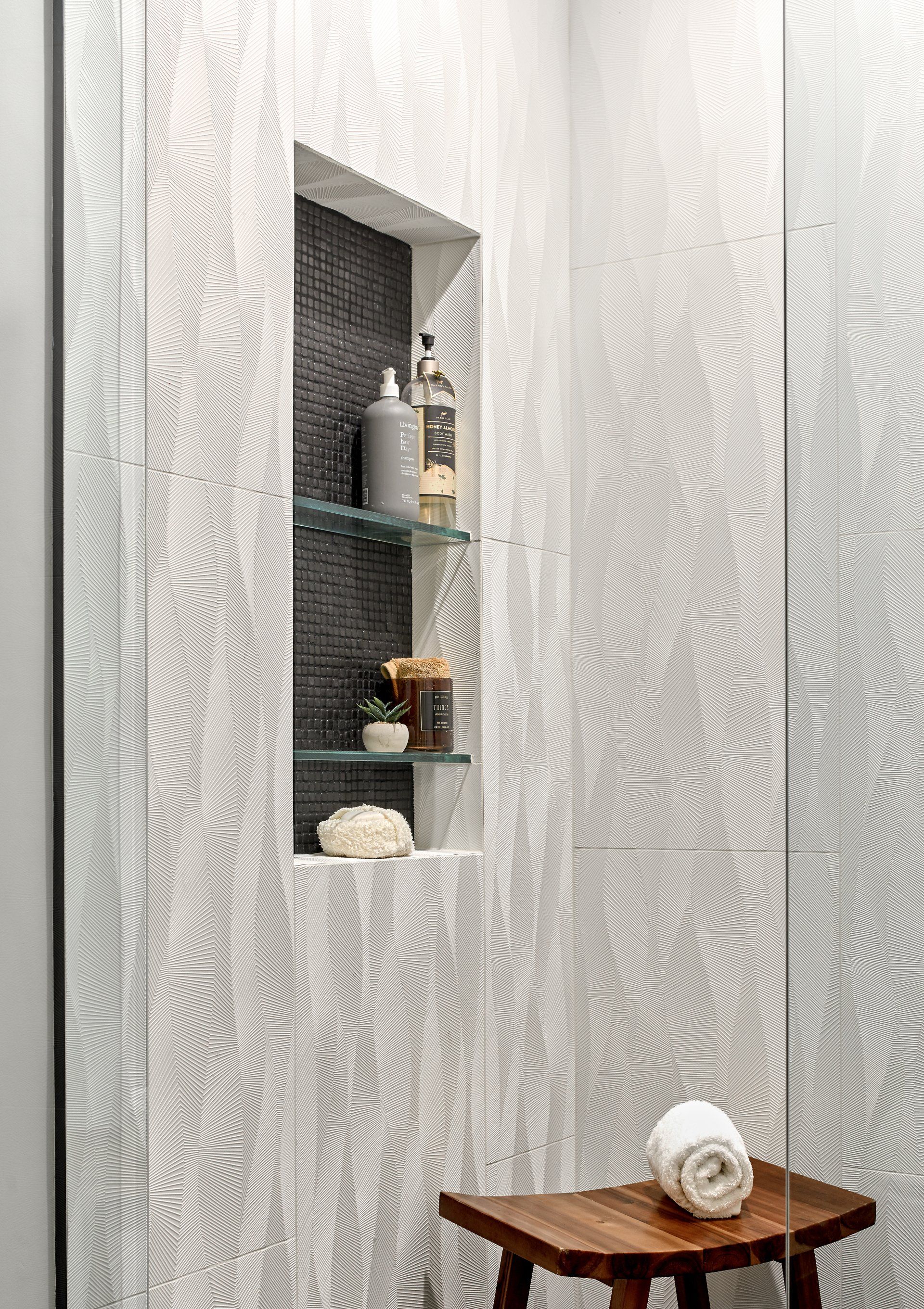 A bathroom with a wooden stool and a mirror.