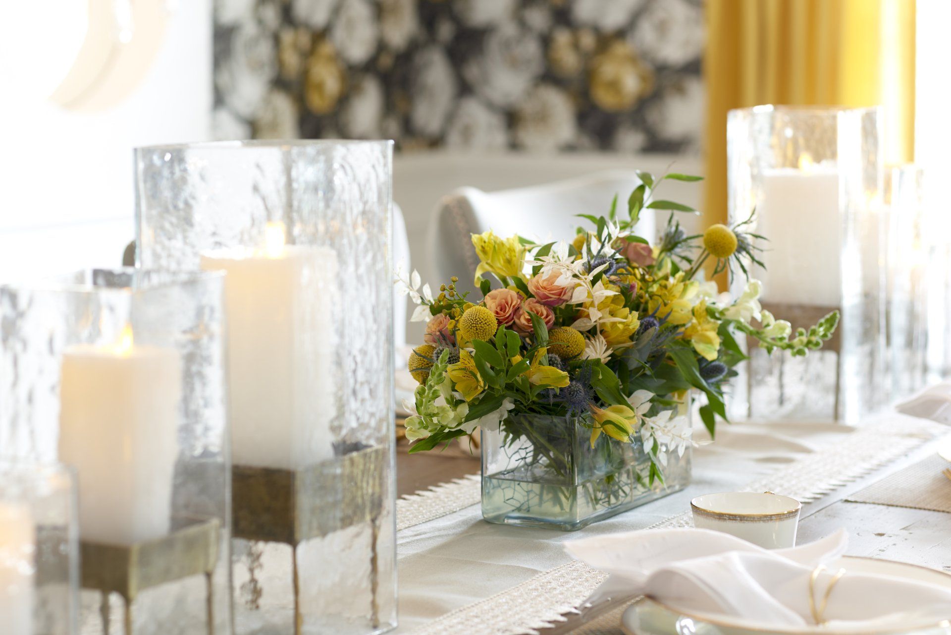 A table with a vase of flowers and candles on it.
