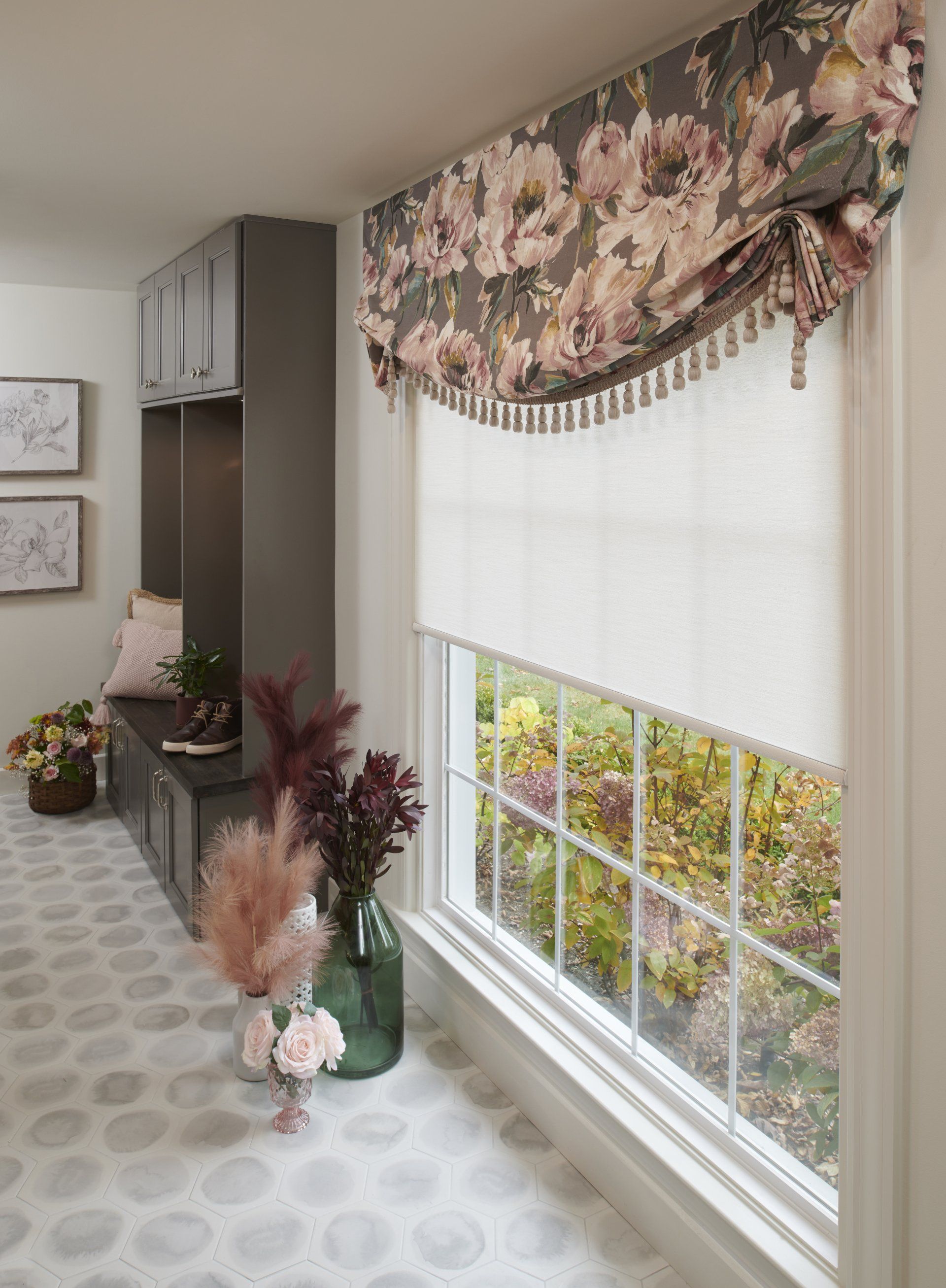 A living room with a large window and a floral valance.