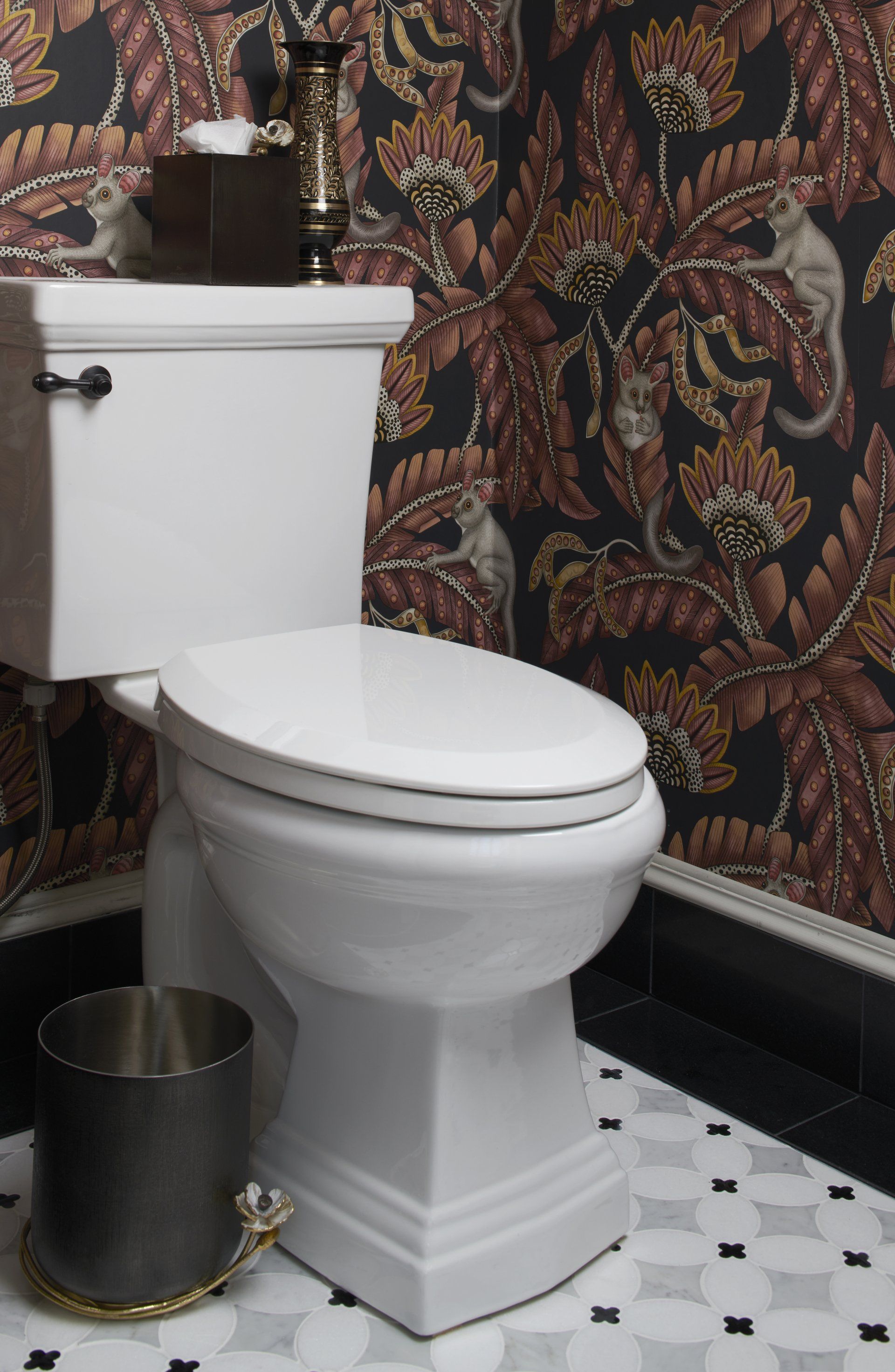 A toilet in a bathroom with a floral wallpaper