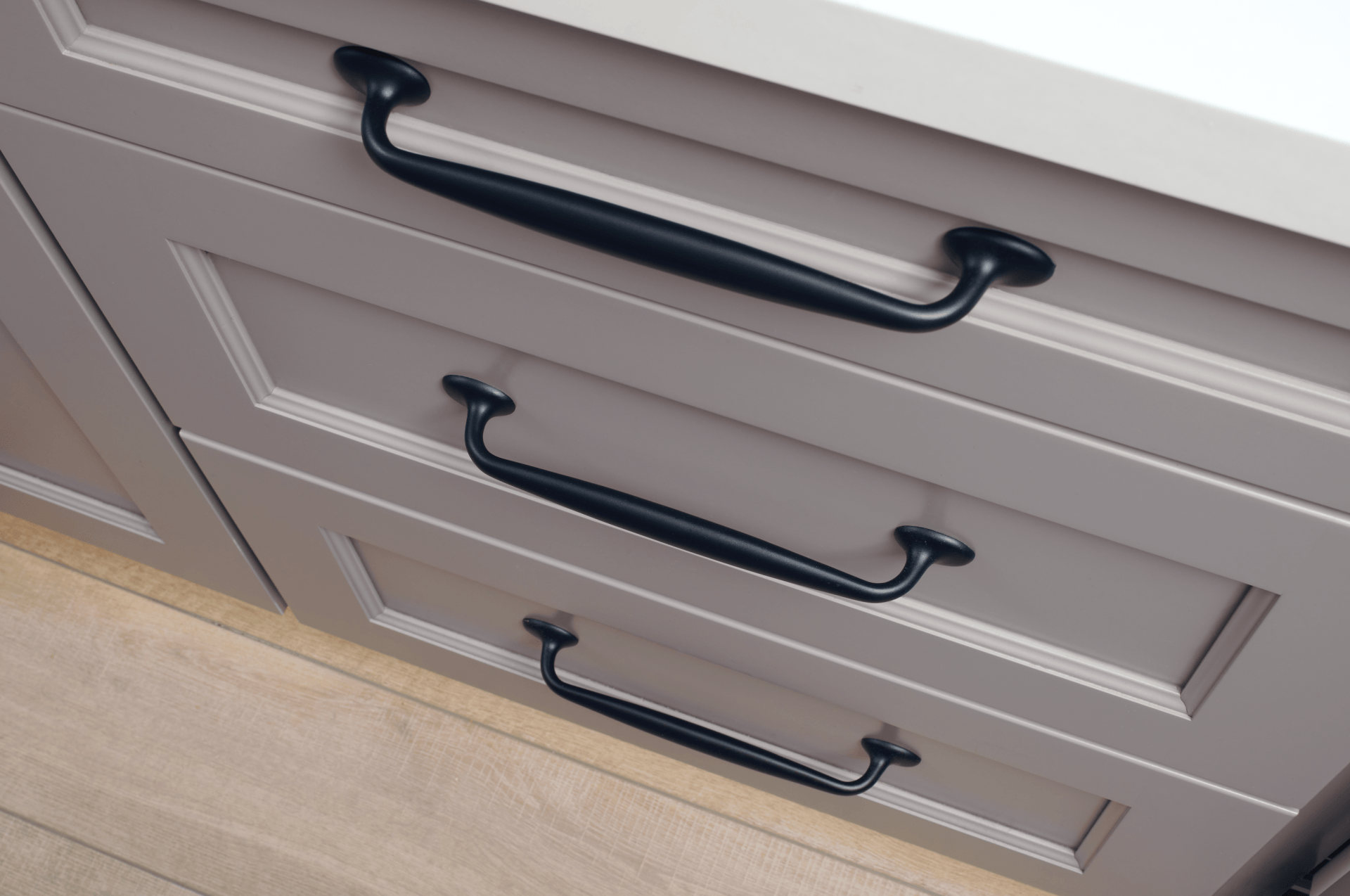 A close up of a kitchen cabinet with black handles.