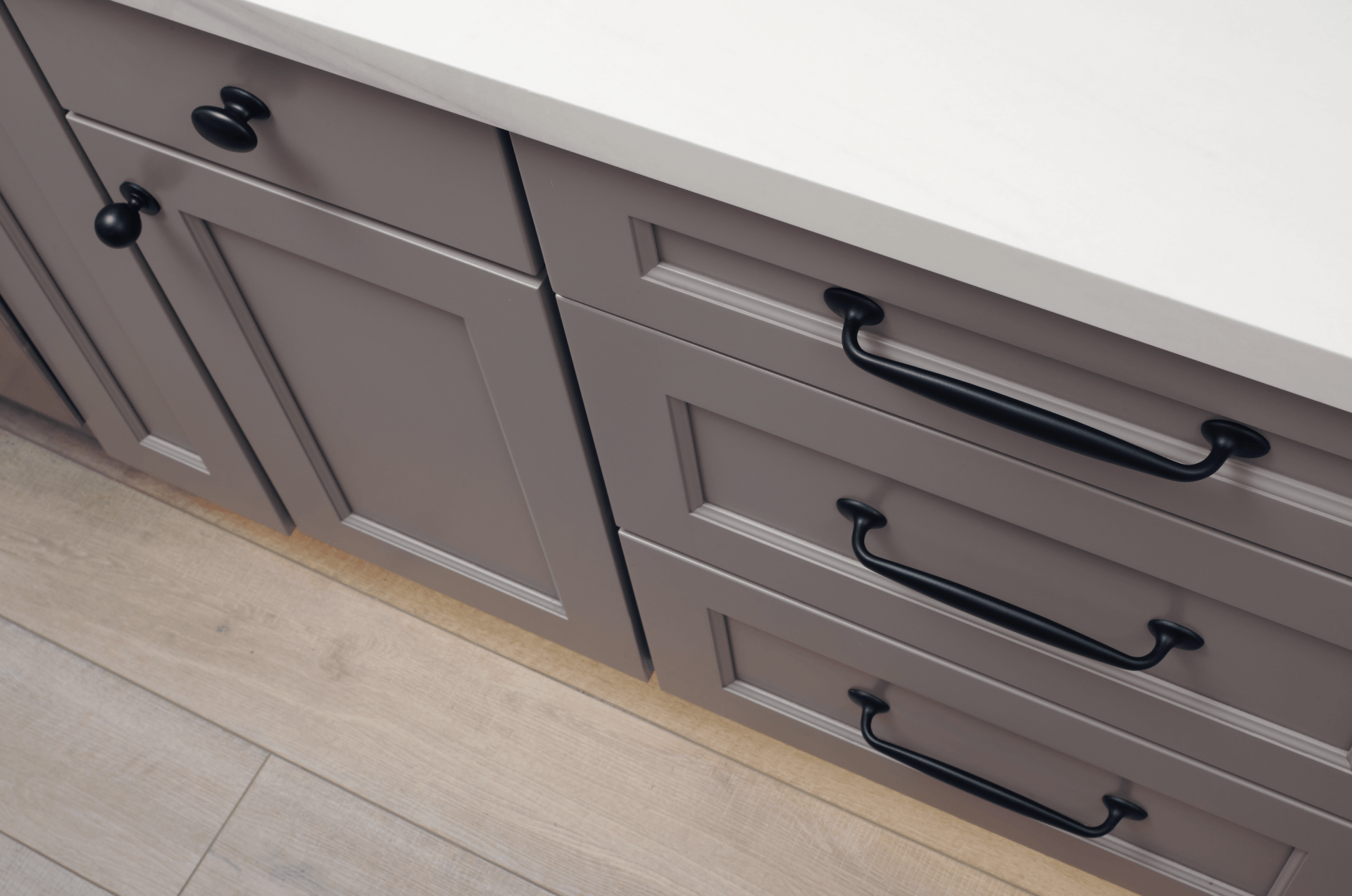 A kitchen with gray cabinets and black drawer handles.