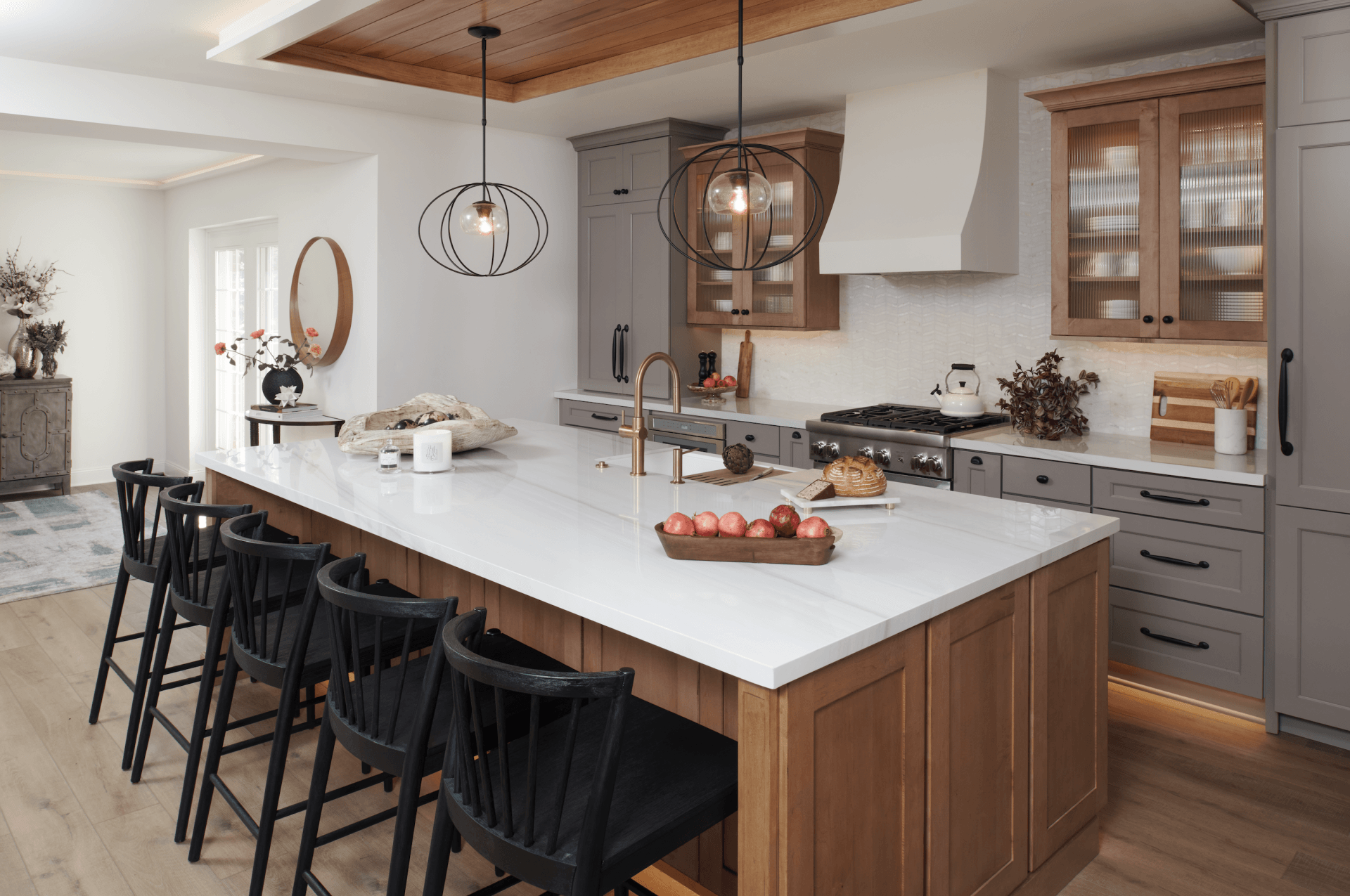 A kitchen with a large island and stools in it.