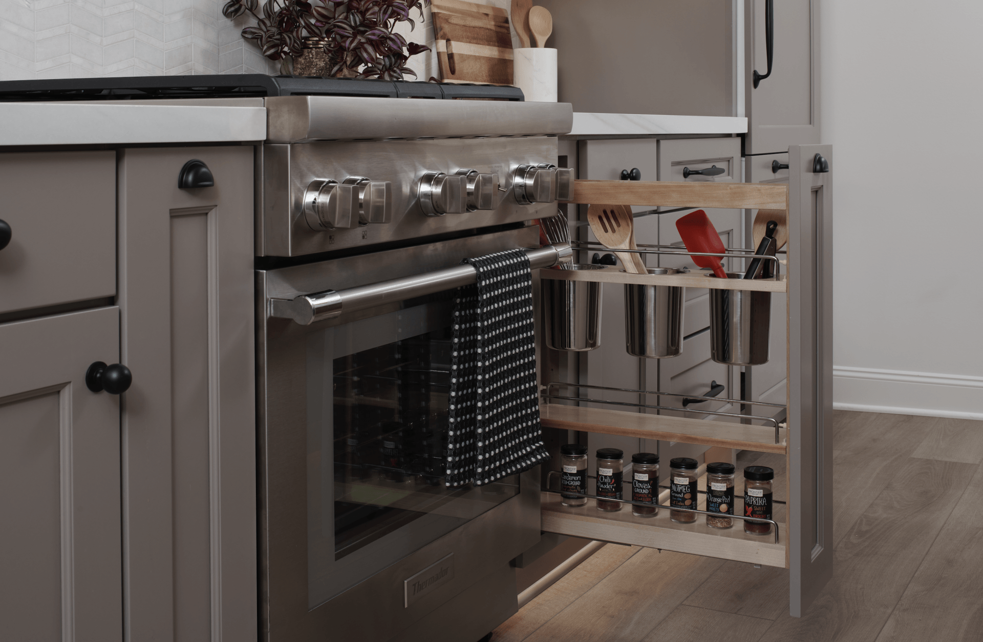 A kitchen with a stainless steel stove and a pull out spice rack.