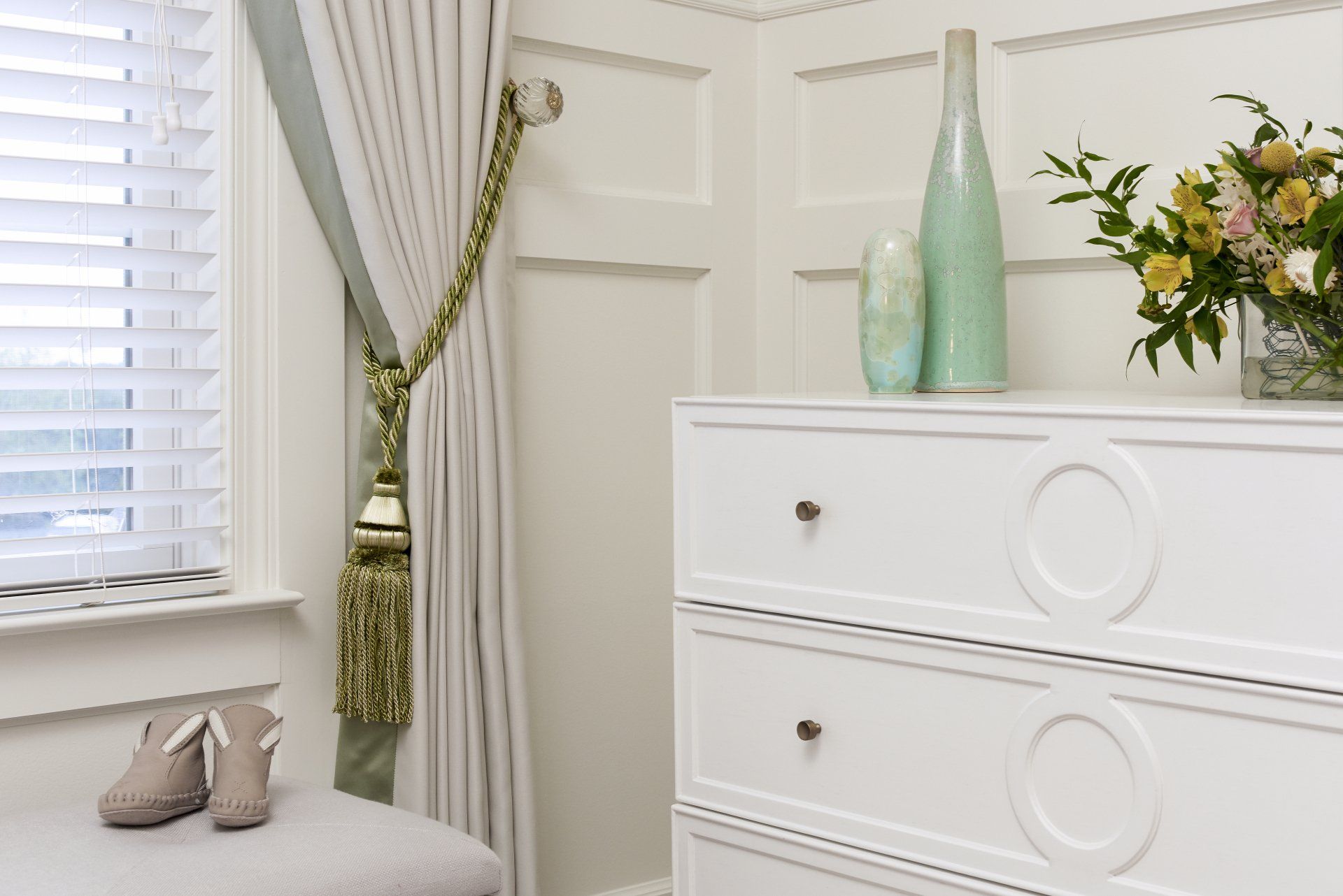 A white dresser with a vase of flowers on top of it