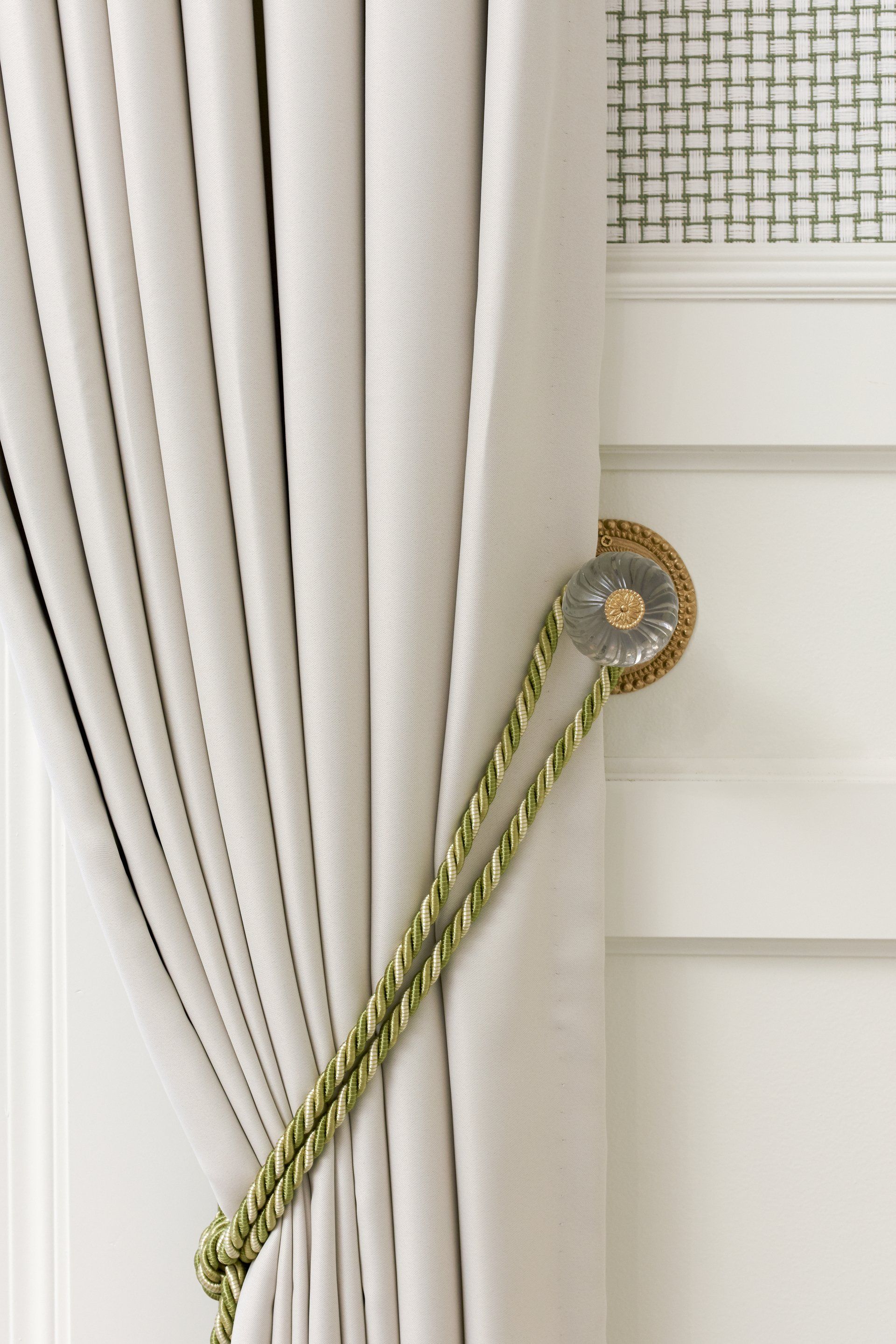 A close up of a white curtain with a green rope tie