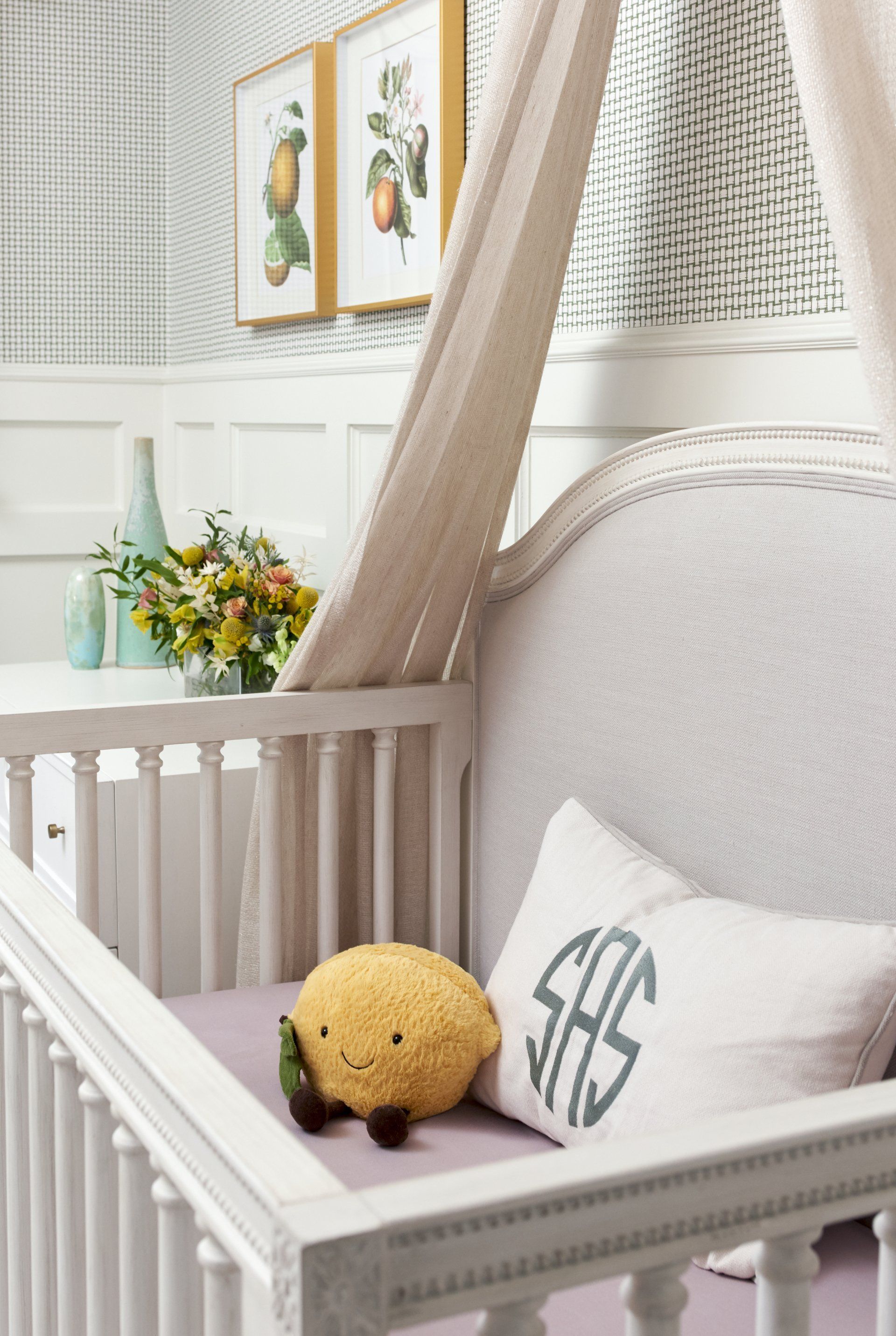 A white crib with a monogrammed pillow and a stuffed animal.