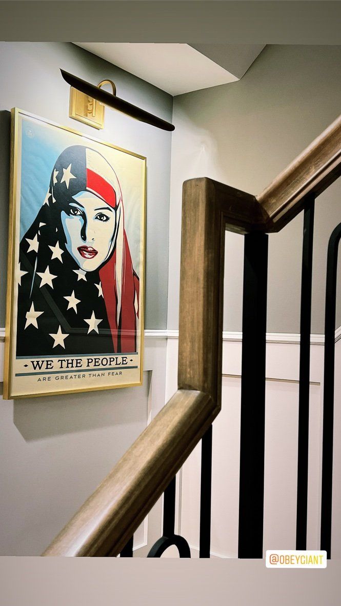 A picture of a woman in a hijab is hanging on a wall next to a staircase.