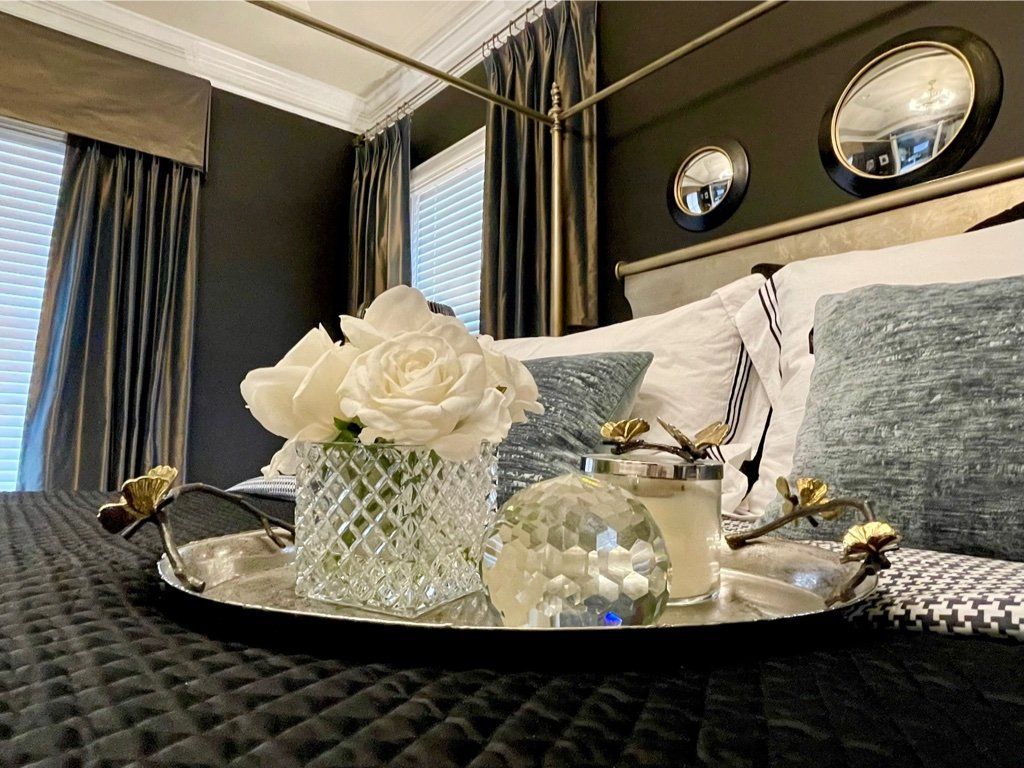 There is a tray with flowers and candles on it on the bed.