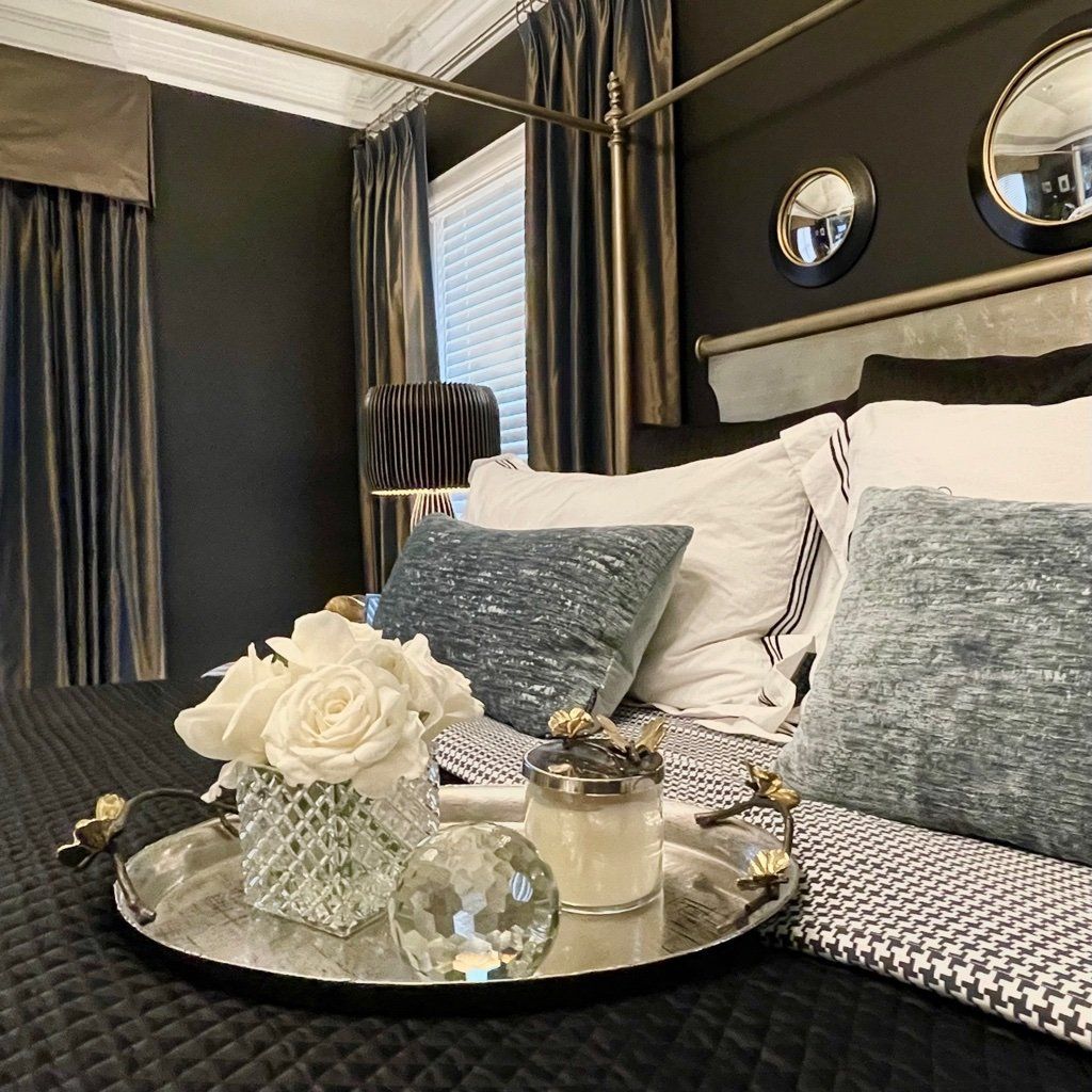 A bedroom with a canopy bed , a tray with flowers and a candle on it.