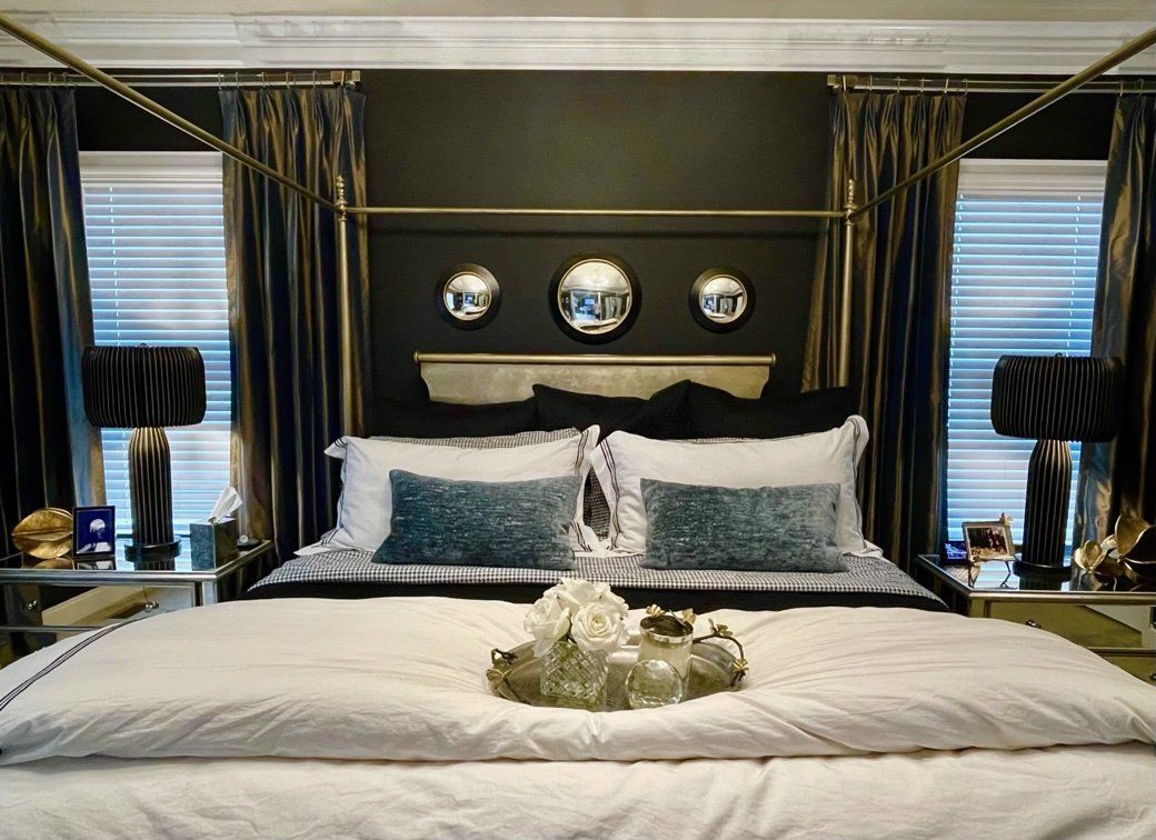 A bedroom with a canopy bed and a tray of flowers on the bed.
