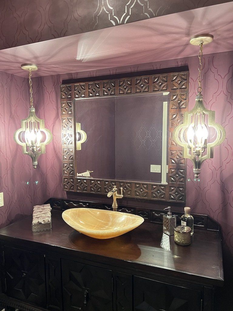 A bathroom with purple walls and a sink and mirror
