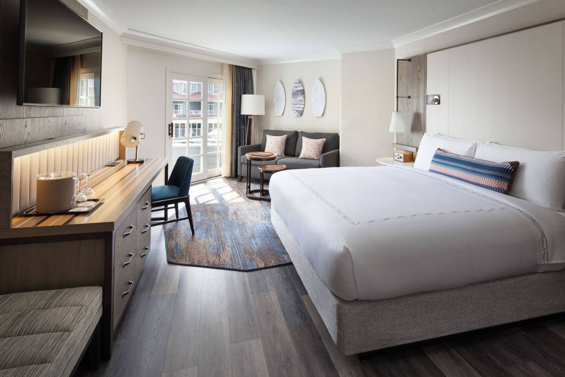 A hotel room with a king size bed , couch , desk and television.