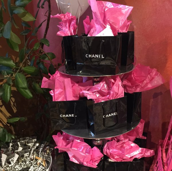 A stack of black chanel bags covered in pink tissue paper
