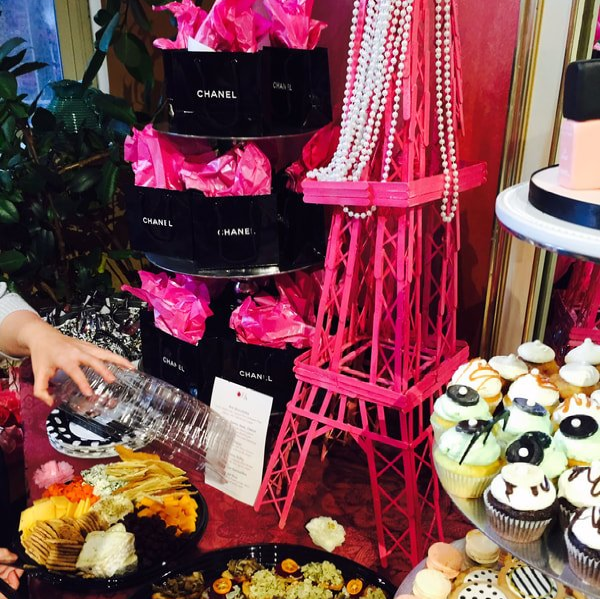 A pink eiffel tower is surrounded by pink boxes that say chanel