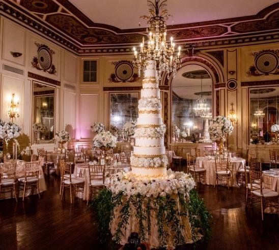 A large wedding cake is on a table in a large room