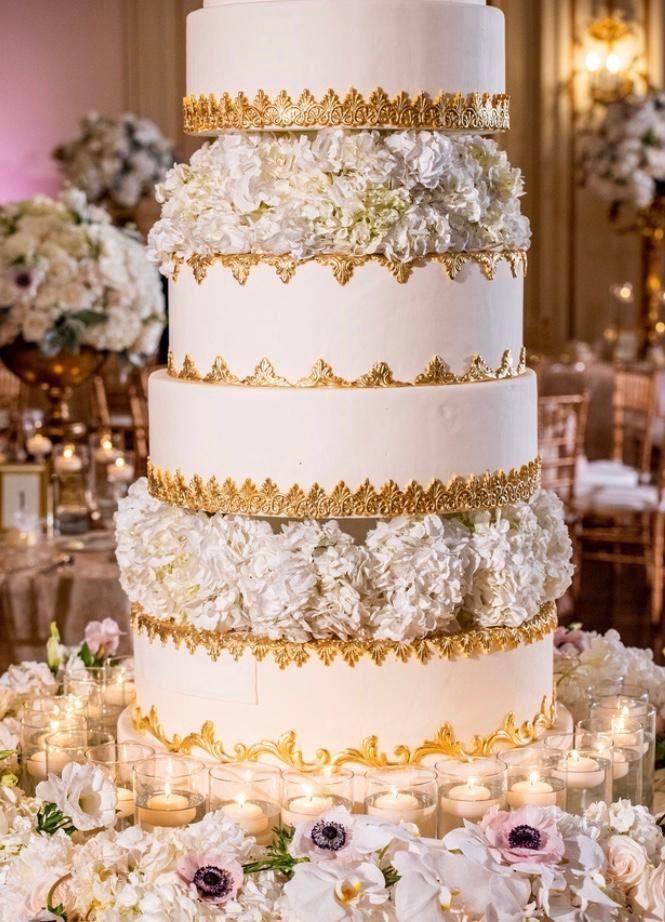 A wedding cake is sitting on top of a table with candles and flowers.