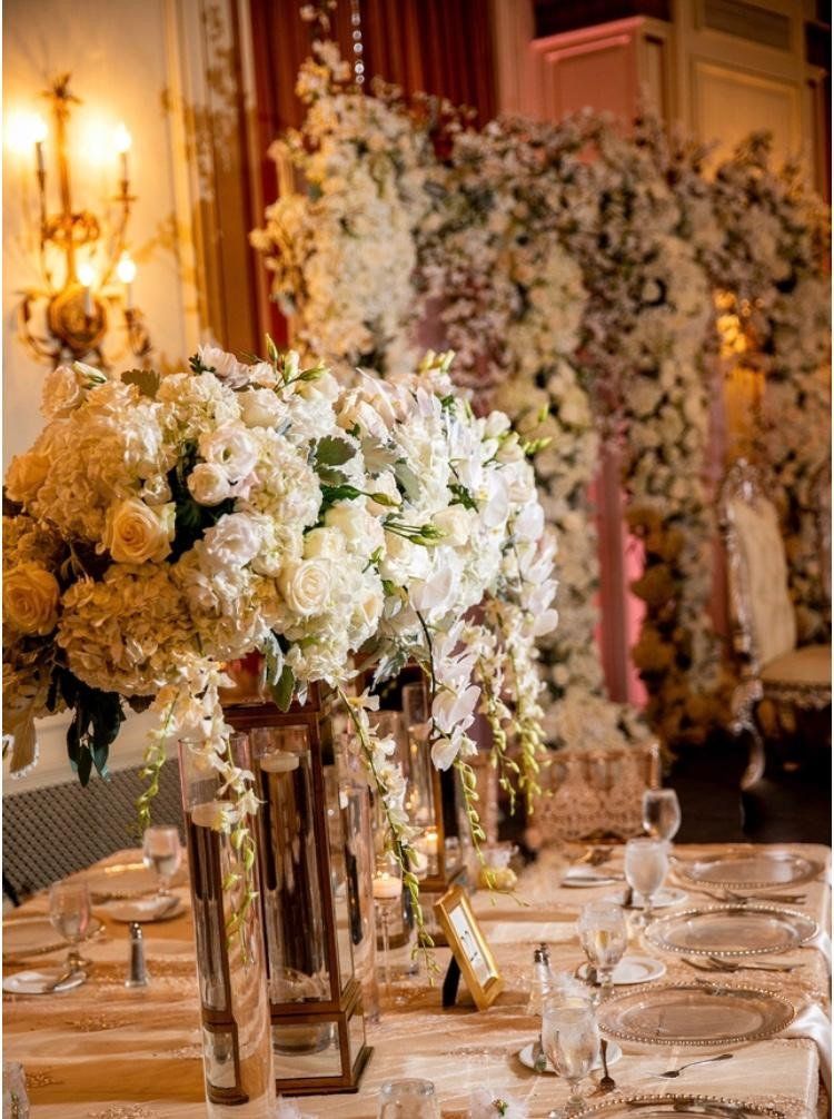 A table set for a wedding reception with flowers in vases on it.