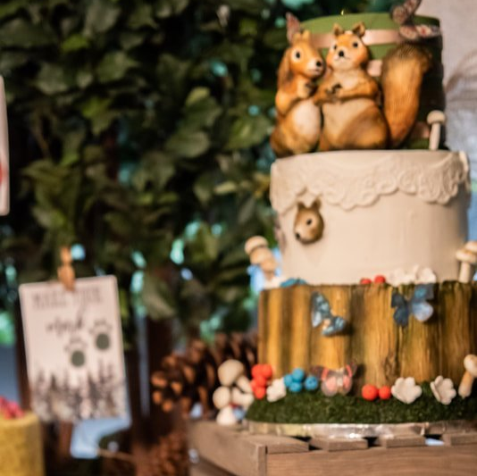 A cake with squirrels on top of it is on a table.