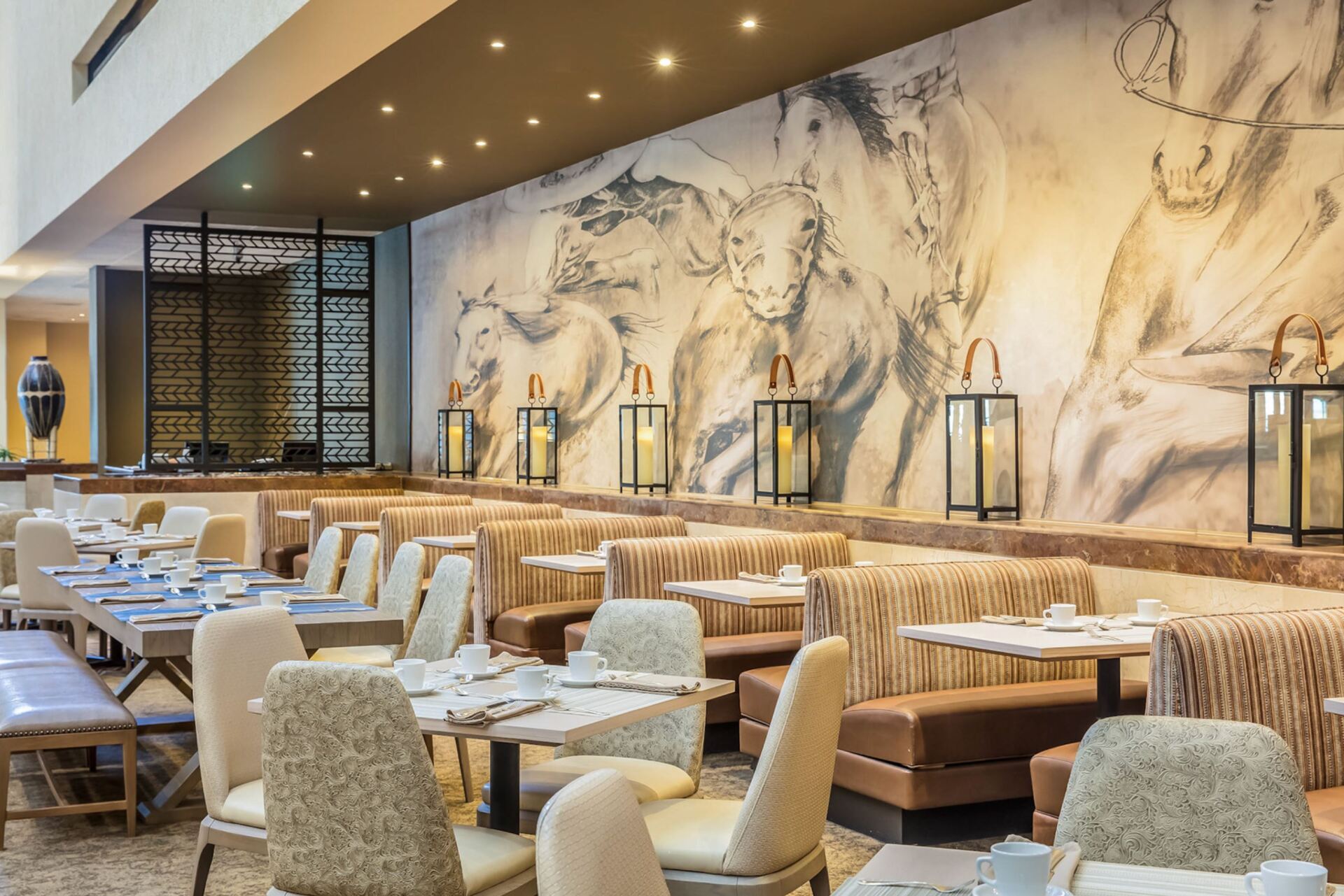 A restaurant with tables and chairs and a large mural on the wall.