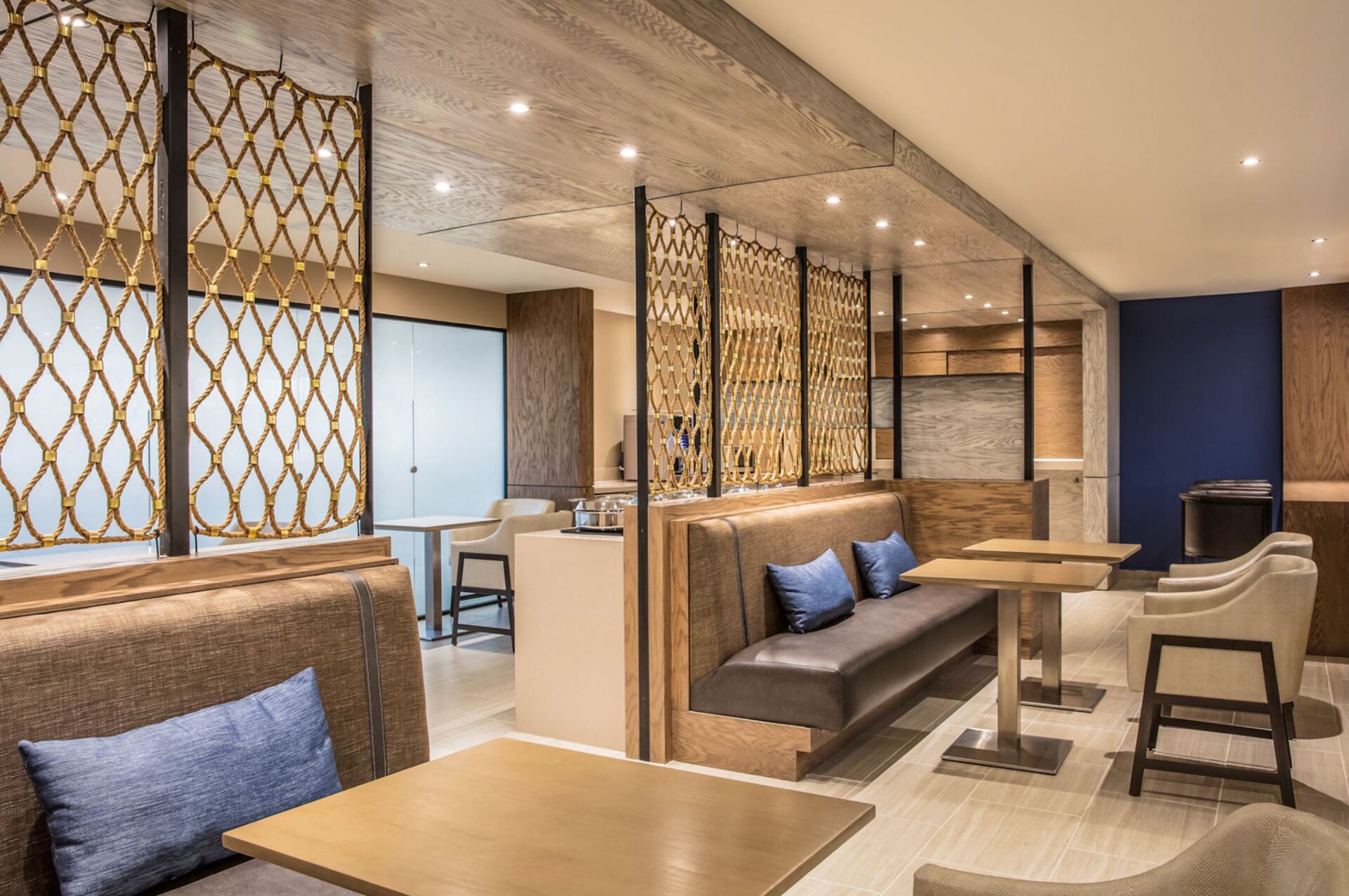 A restaurant with tables , benches , chairs and blue pillows.