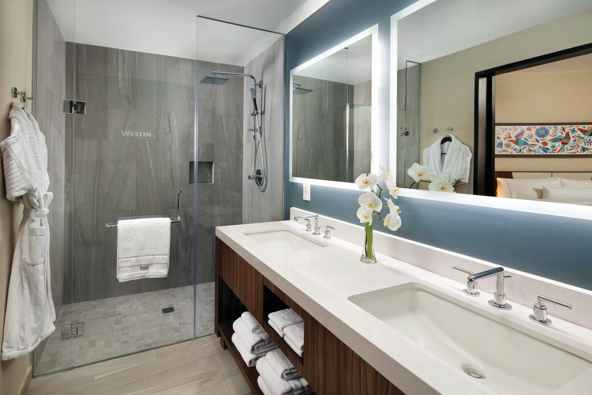 A bathroom with two sinks and a walk in shower.