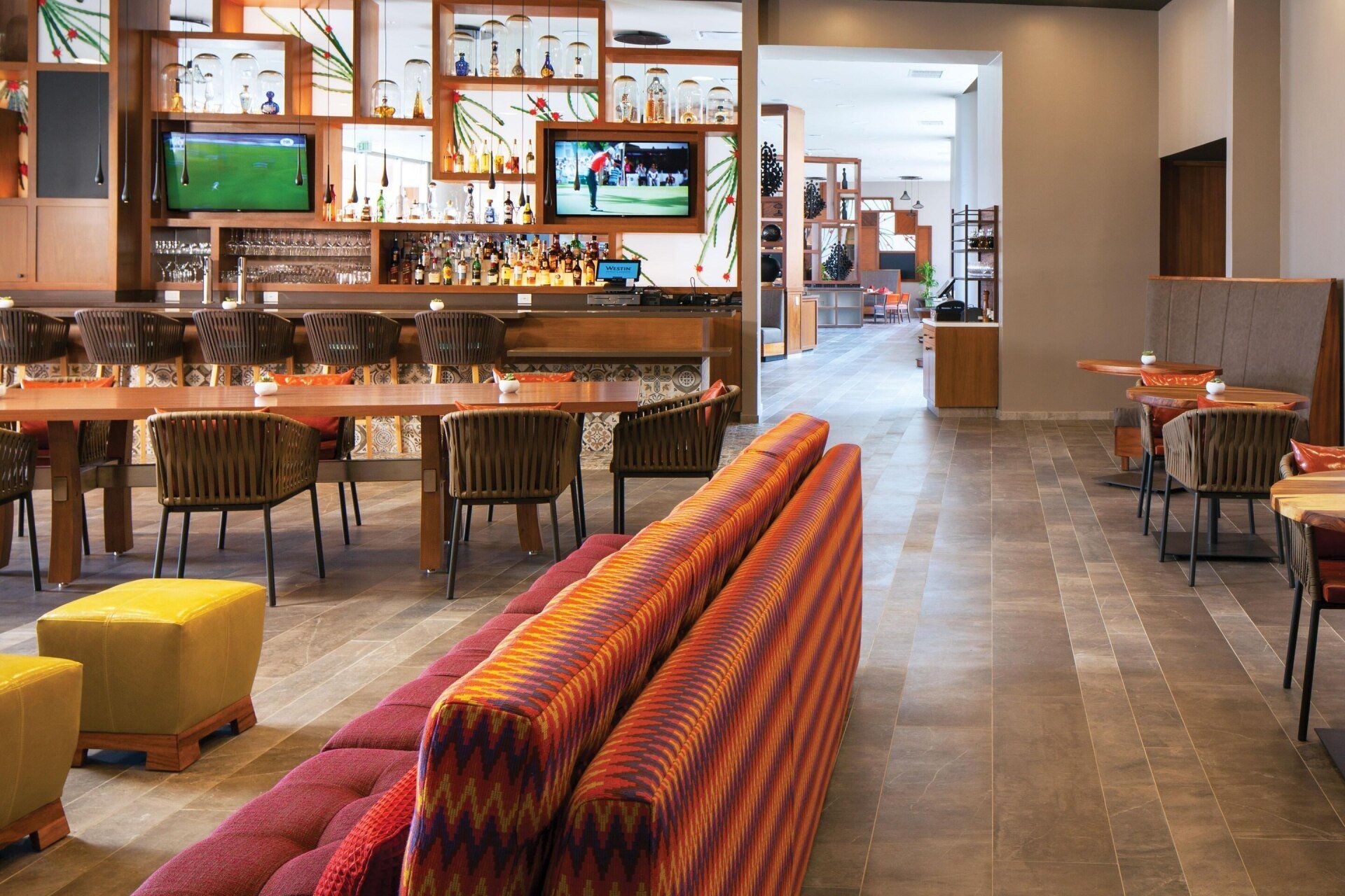 A restaurant with tables , chairs , a couch and a bar.