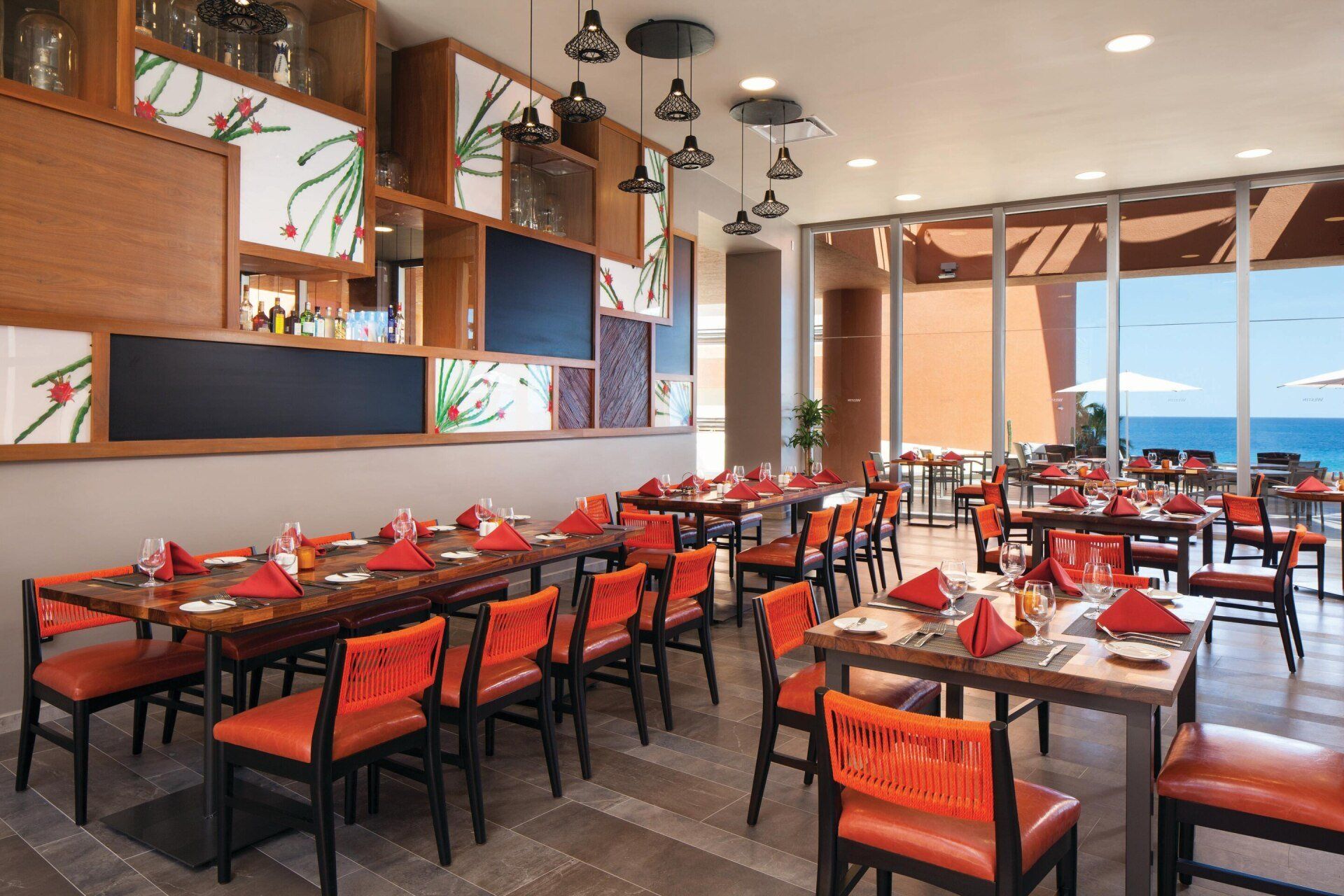 A restaurant with tables and chairs and a view of the ocean.