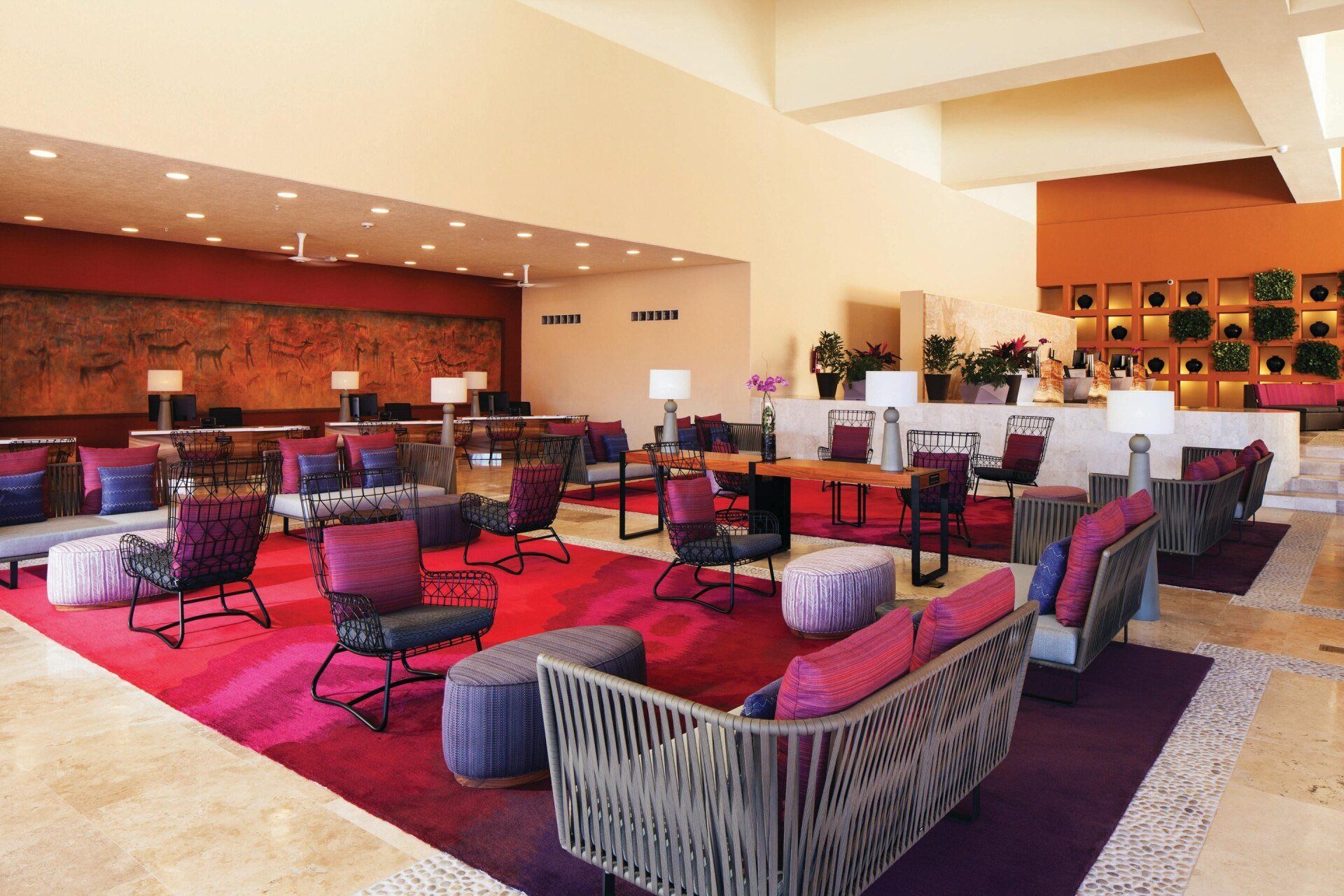 A large lobby with a lot of furniture and a red rug.