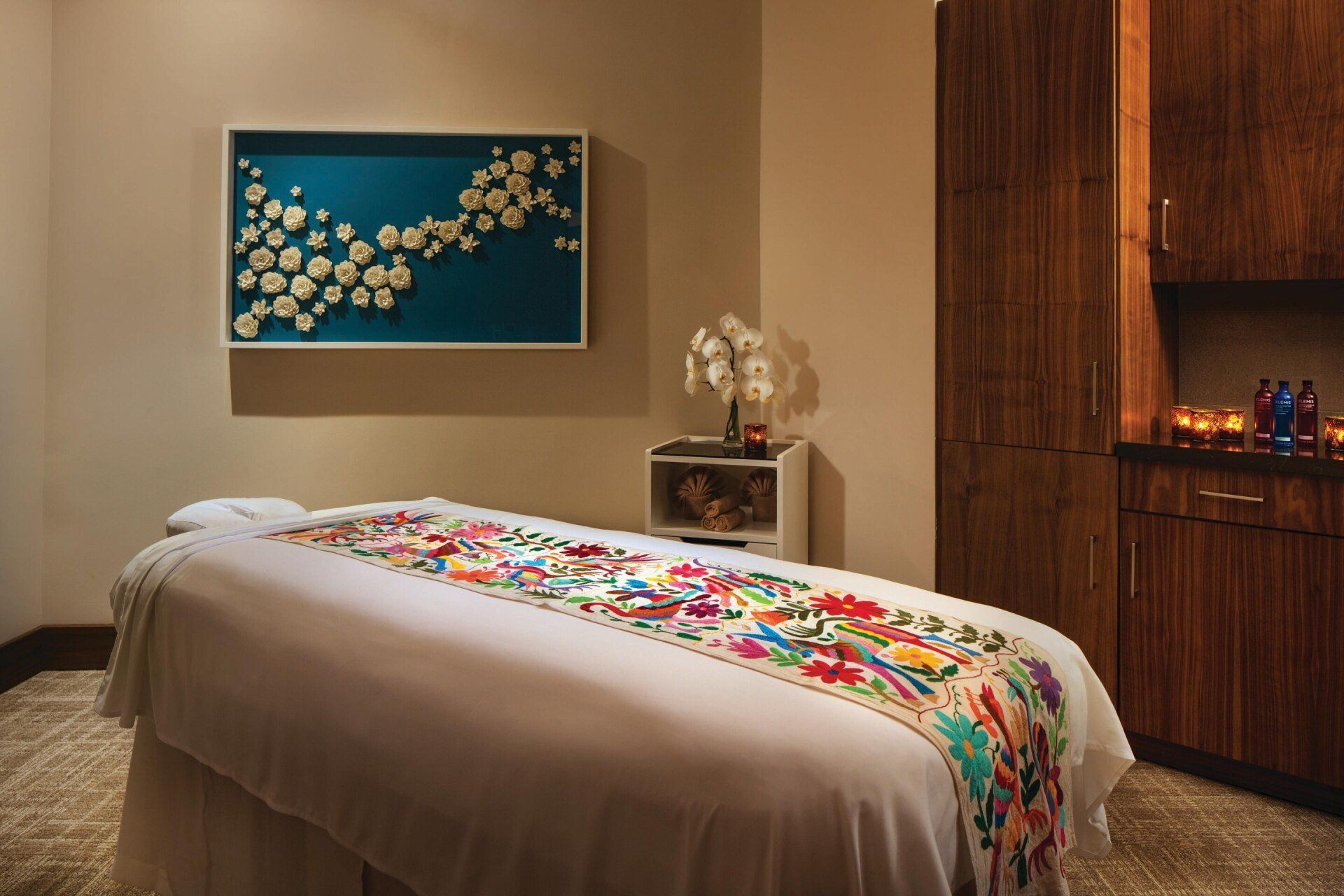A massage table in a room with a picture on the wall above it.