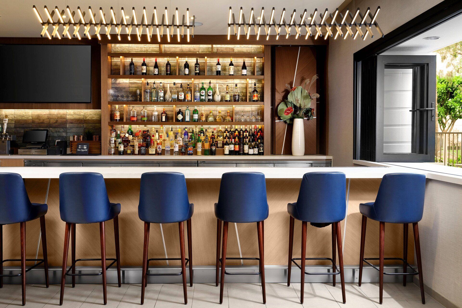 A bar with a lot of bottles on it and blue chairs