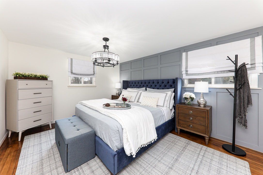 A bedroom with a bed , dresser , nightstand and rug.