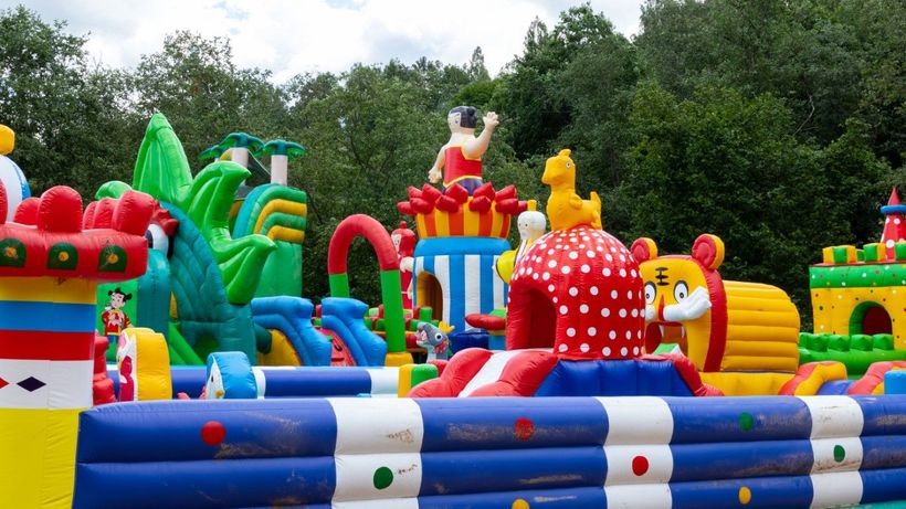 A backyard packed with colorful inflatables, toys, and slides, a playground paradise for kids.