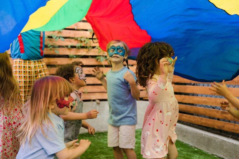 kids with colorful face paintings, smiling and enjoying their playful transformations.