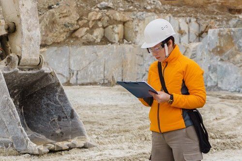Expert mining engineer with a clipboard at an active mining site