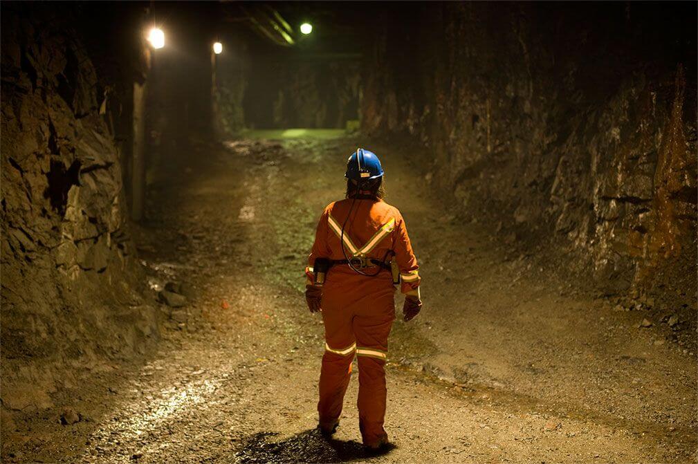 Miner standing in a mine shaft assess dilution control