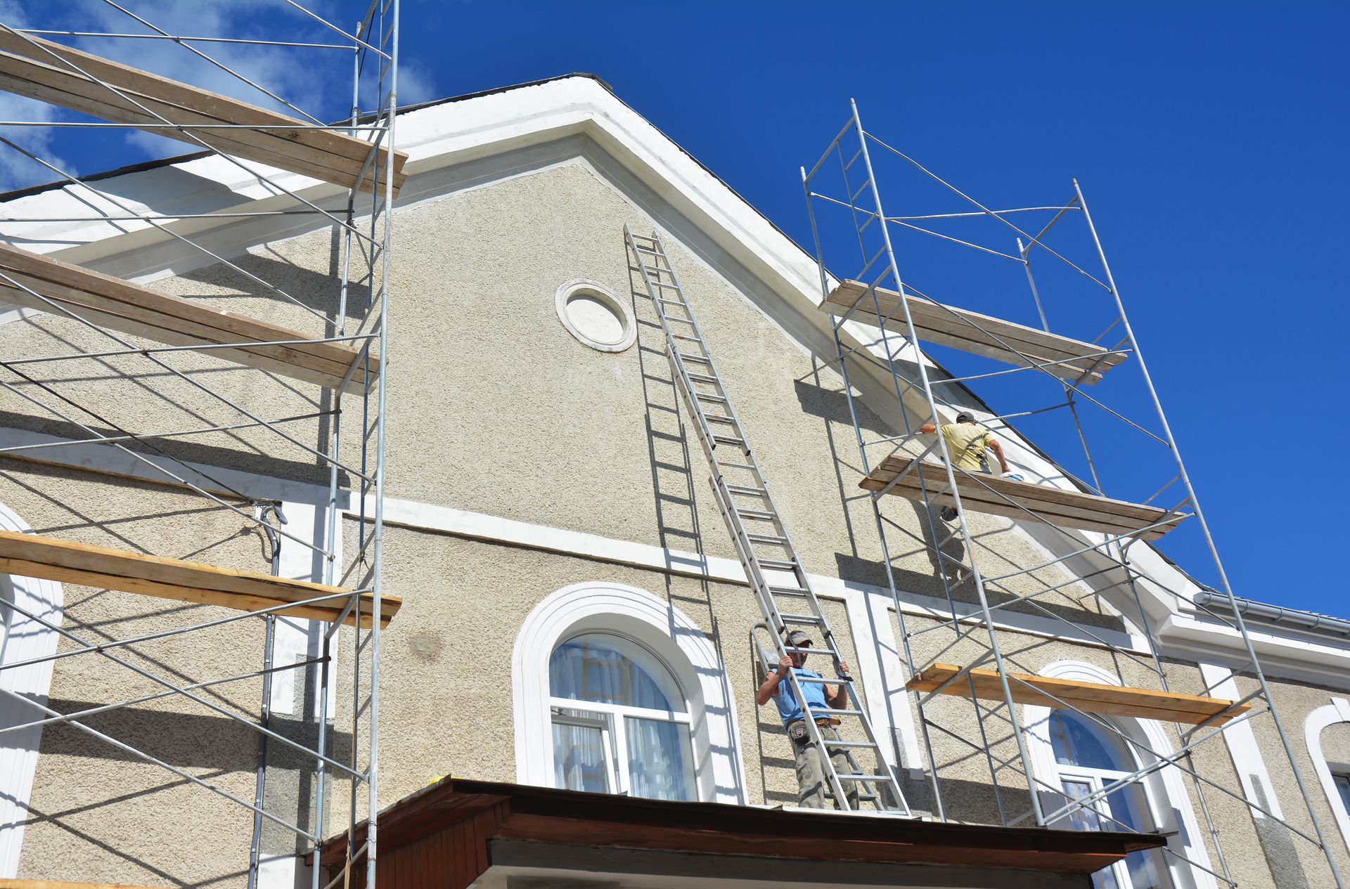 Scaffolding and ladders on a house under construction against a bright blue sky