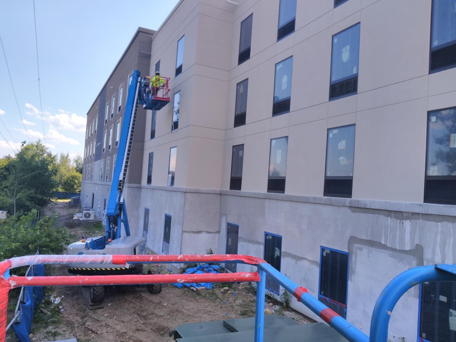 Person using a trowel to apply stucco to an exterior wall of a building under construction.