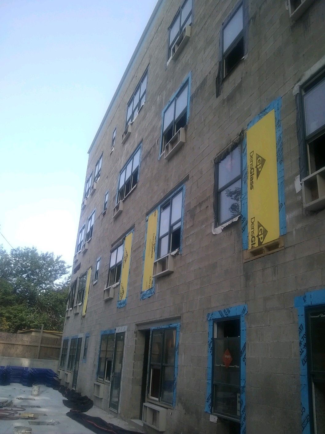 A construction worker is holding a clipboard in front of a building under construction.