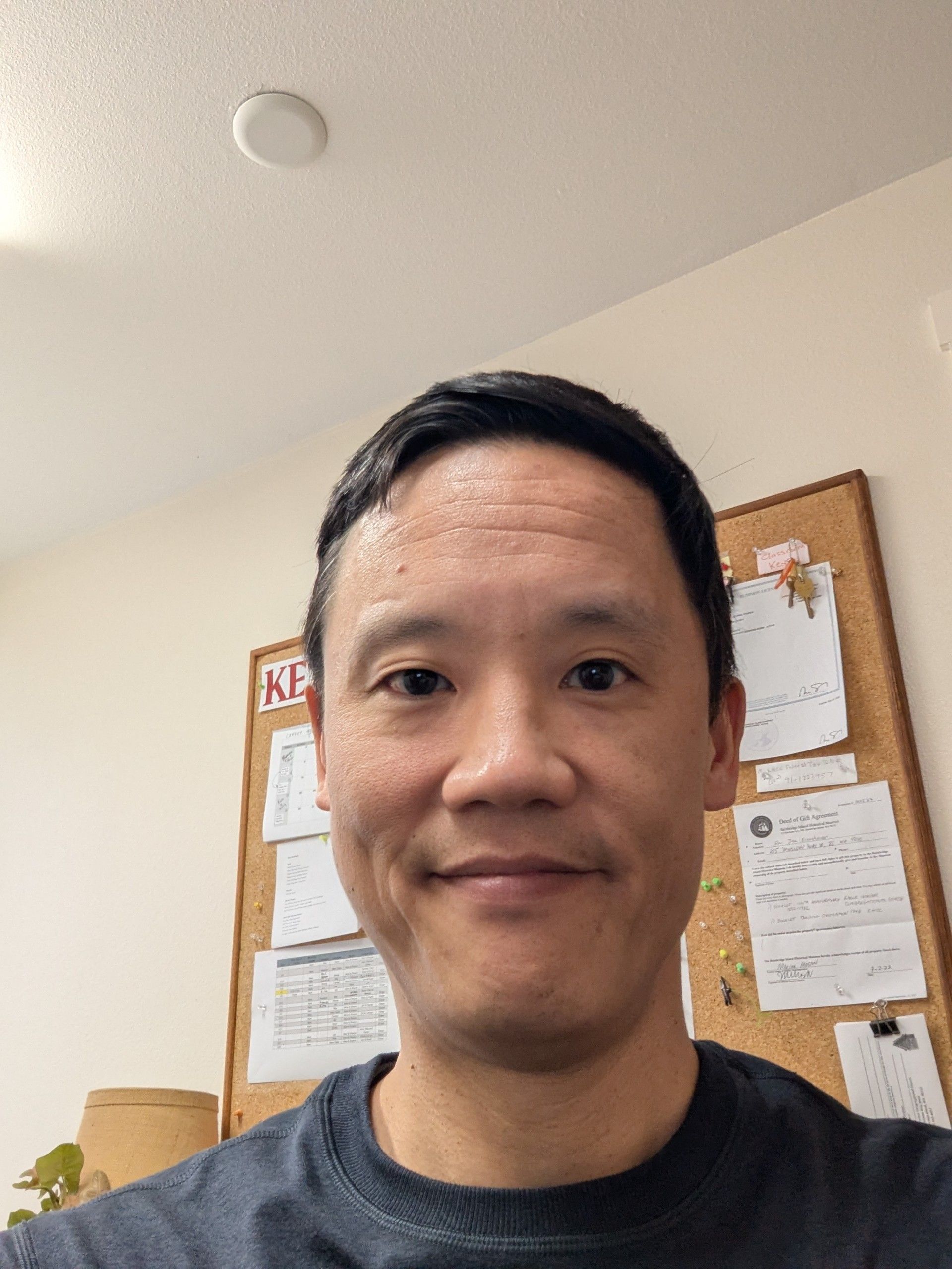 A woman wearing a blue shirt and a red necklace smiles for the camera.