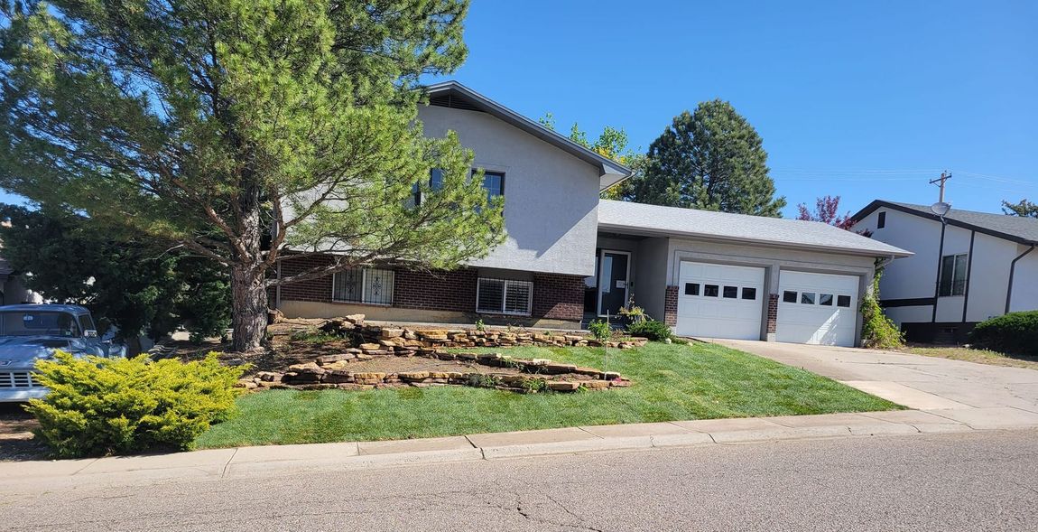 A large house with a lot of grass and trees in front of it.