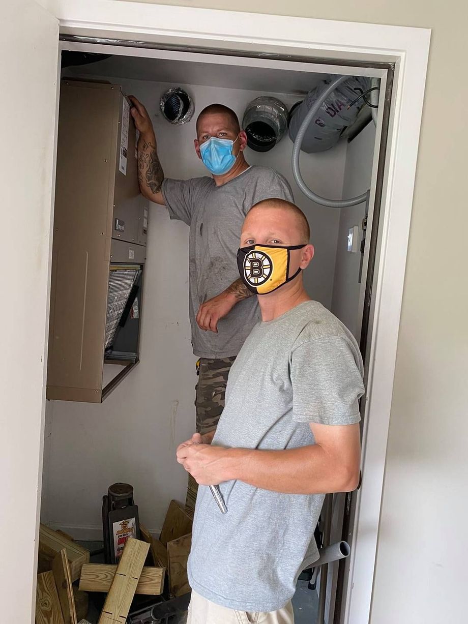 Two men wearing face masks are standing in a doorway.