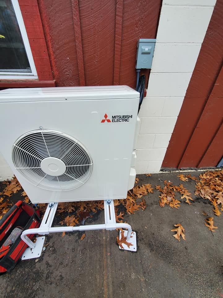 A white air conditioner is sitting on the side of a house.