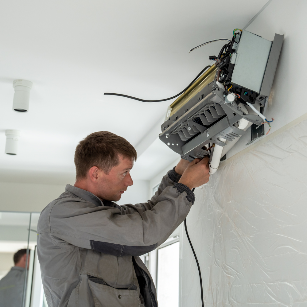 A man is working on an air conditioner on a wall