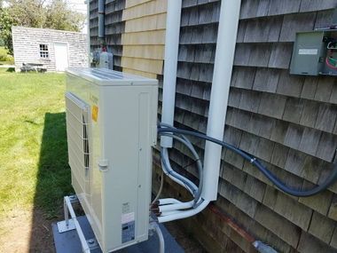 A white air conditioner is sitting on the side of a house.