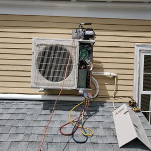 An air conditioner is being installed on the side of a house.